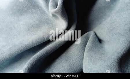 Close-up of velvety thick fabric for curtains of gray-blue color pleated with the play of chiaroscuro Stock Photo