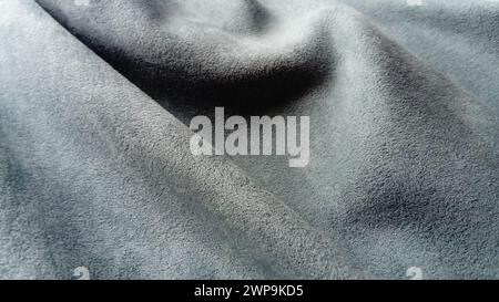 Close-up of velvety thick fabric for curtains of gray-blue color pleated with the play of chiaroscuro Stock Photo