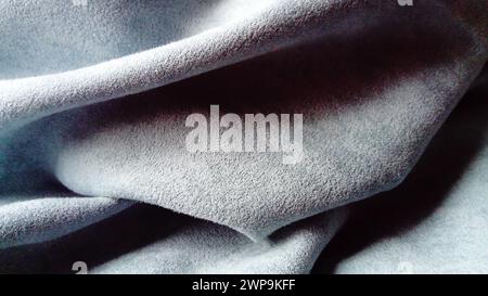Close-up of velvety thick fabric for curtains of gray-blue color pleated with the play of chiaroscuro Stock Photo