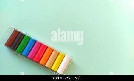 Multi-colored new plasticine in plastic packaging on a light green background. Plasticine plates of red, pink, green, white, yellow, brown, blue Stock Photo