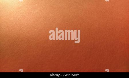 A sheet of thick paper of bright orange color. Close-up. Background intense shade. Natural lateral lighting. Fine cardboard or paper texture. Light Stock Photo