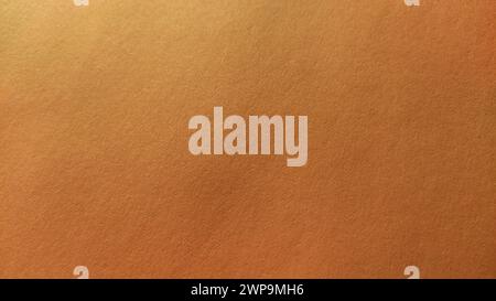 A sheet of thick paper of bright orange color. Close-up. Background intense shade. Natural lateral lighting. Fine cardboard or paper texture. Light Stock Photo