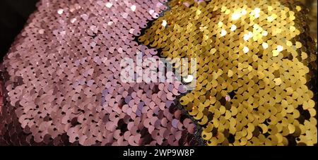 Gold, pink and multi-colored sparkles on the fabric. Rainbow blurred background. Shiny, sparkling in the sun, multi-colored sequins. Sewing Stock Photo