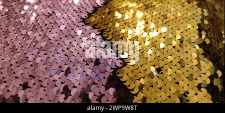 Pink , gold and multi-colored sparkles on the fabric. Rainbow blurred background. Shiny, sparkling in the sun, multi-colored sequins. Sewing Stock Photo