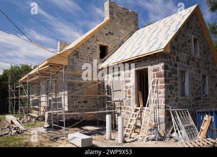 Restoration work on an old 1800s Canadiana style fieldstone home in summer, Montreal, Quebec, Canada. Stock Photo