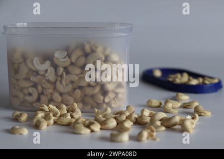 A heap of golden roasted cashews in a plastic container. Perfect for snacks and culinary delights, capturing the essence of premium quality and irresi Stock Photo
