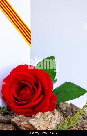 Red rose on the bark of a tree and a blank page in the background and a ribbon with the flag of Catalonia Stock Photo