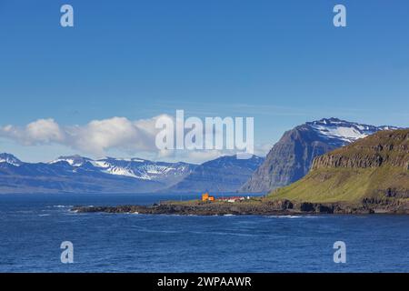 Rugged mountains and orange lighthouse at Skalanes along the fjord Seyðisfjörður / Seydisfjoerdur in summer, Eastern Region / Austurland, Iceland Stock Photo