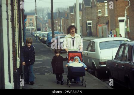 1980s working class family UK.  Father out pushing a pram along with two older children. Subway Street in the Hessle Road area of town was a traditional working class enclave and home to fishermen and docker workers. Hull, Humberside, northern England 1980 HOMER SYKES Stock Photo