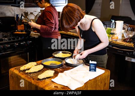 Two women preparing a meal in a modern kitchen on an island counter Stock Photo
