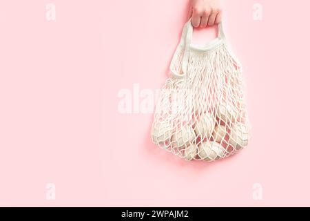Eco-friendly concept with wooden eggs in cotton bag on pink background. Easter holiday Stock Photo
