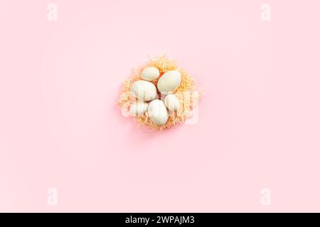 Wooden eggs lying on artificial nest in the center on pink background. Easter eco-friendly concept Stock Photo