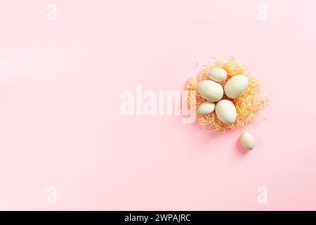 Wooden eggs lying on artificial nest on pink background. Easter eco-friendly concept Stock Photo