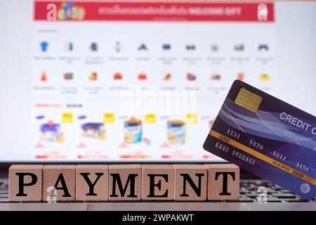 Blue credit card and wood cube letter put on computer laptop on blurred web shopping online background with spending via credit card Stock Photo