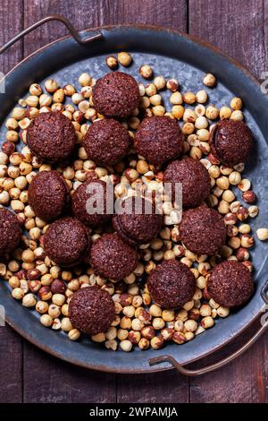 Baci de Alassio, Italian cookies made from nut dough filled with chocolate ganache on a background of shelled hazelnuts. Stock Photo