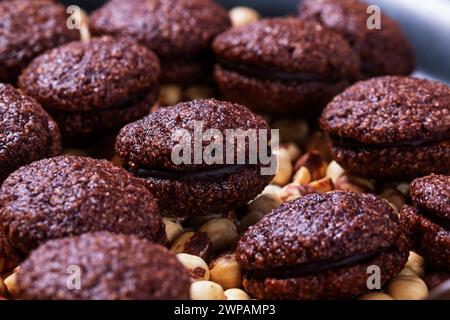 Baci de Alassio, Italian cookies made from nut dough filled with chocolate ganache on a background of shelled hazelnuts. Stock Photo