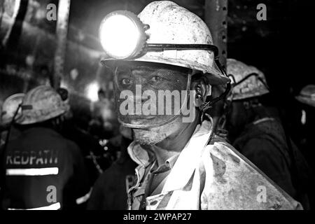 A grayscale shot of a night workers with flashlight on their head Stock Photo