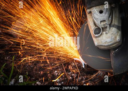 Angle grinder radial machine works with bright sparks stream, close up photo with selective soft focus and motion blur Stock Photo