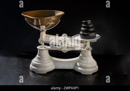 Old obsolete manual weighing scales and Iron Brass Tray with set of cast iron weights. Classic weight scale Isolated on dark background, Antique balan Stock Photo