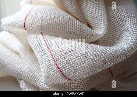 White coarse cotton or linen curtains made of weaves of thin threads. Simple compact economical apartment interior. Window decoration in the room. Red Stock Photo
