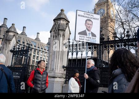 As Conservative party Chancellor Jeremy Hunt delivers his pre-election budget, an anti-government protester stands with a parody placard outside parliament, on 6th March 2024, in London, England. Stock Photo