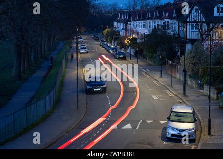 Light trails from passing vehicles along a dark suburban street lined with residential south London properties and parked cars in Lambeth, on 2nd March 2024, in London, England. Stock Photo