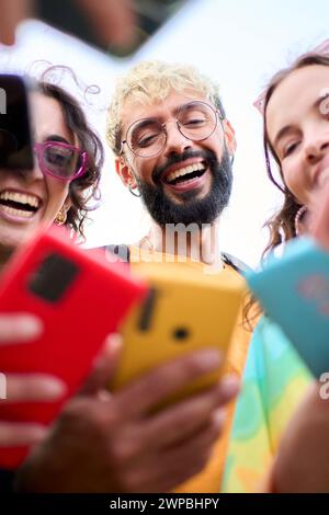 Group happily celebrating, sharing smiles, and taking selfies with cell phones Stock Photo