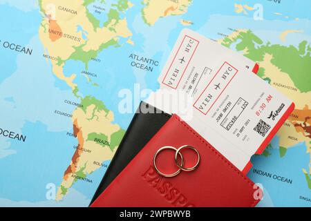 Honeymoon concept. Plane tickets, passports and golden rings on world map, top view Stock Photo