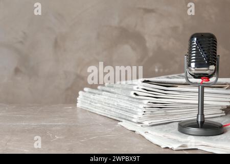 Newspapers and vintage microphone on marble table, space for text. Journalist's work Stock Photo