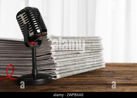 Newspapers and vintage microphone on wooden table. Journalist's work Stock Photo