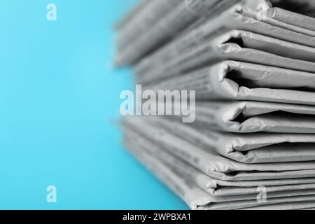 Stack of newspapers on light blue background, closeup. Journalist's work Stock Photo
