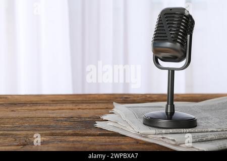 Newspapers and vintage microphone on wooden table, space for text. Journalist's work Stock Photo