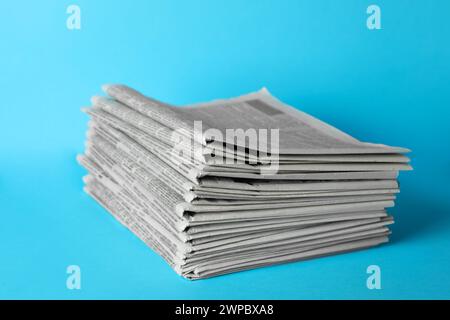 Stack of newspapers on light blue background. Journalist's work Stock Photo