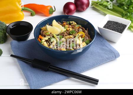 Stir-fry. Delicious cooked noodles with chicken and vegetables in bowl served on white wooden table Stock Photo