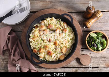 Delicious scallop pasta with onion served on wooden table, flat lay Stock Photo