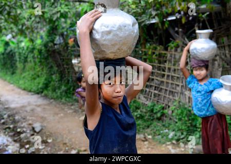 Young Arakanese girls carrying water jugs back to their village in Mrauk-U in Rakhine State, Myanmar. Stock Photo