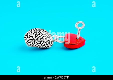 Steel replica of the human brain paired with a heart-shaped padlock, complete with a tiny key isolated on blue backdrop. Unlocking the mysteries of th Stock Photo