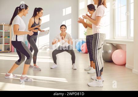 Women In Gym Engage In Squat Exercises Stock Photo