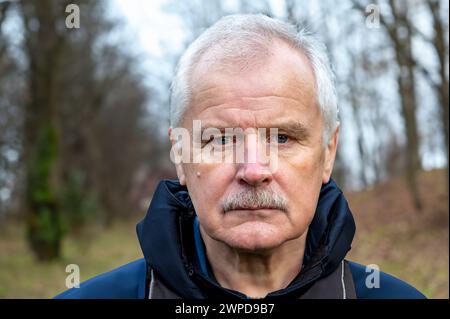 Senior citizen during a hike in the forest looks seriously into the camera. Symbol for aged people staying active. Stock Photo