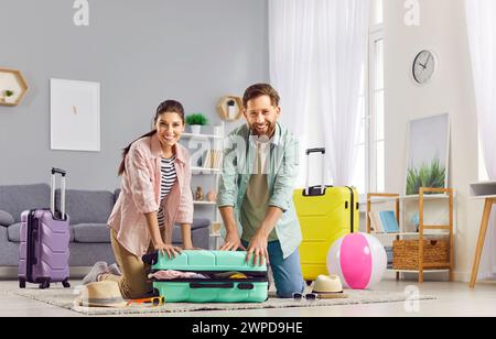 Happy spouses are packing things together in suitcase in preparation for family trip. Stock Photo