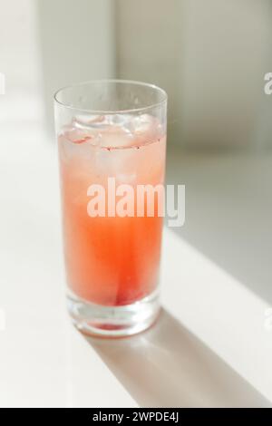 A high glass filled with orange juice and an ice cube Stock Photo