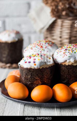 Closeup of decorated Easter cakes and yellow colored eggs on a plate on the table. Stock Photo