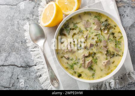 Magiritsa Greek Easter soup with lamb intestines and liver, herbs, seasoned with egg and lemon sauce close-up in a bowl on a marble table. Horizontal Stock Photo