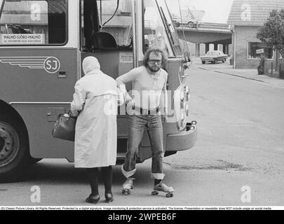 Roller skates 1972. A man wearing roller skates has exited the bus and continues on roller skates. Sweden 1972. Stock Photo
