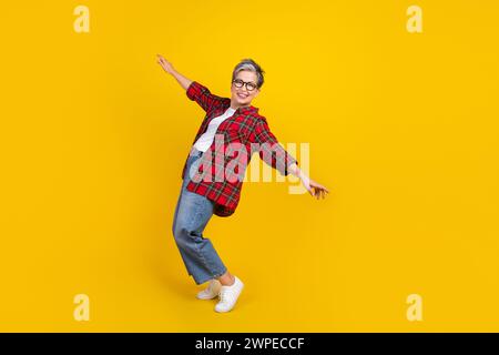 Full body photo of positive pretty lady stand tiptoes dancing empty space isolated on yellow color background Stock Photo