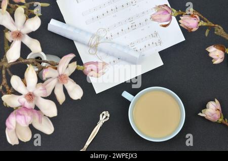White and pink flowers of magnolia, coffee, notes, dark background, flat lay. Stock Photo