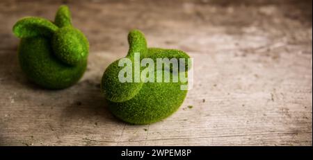 Cute bunnies made of moss on a wooden board for Easter. Copy Space. Stock Photo