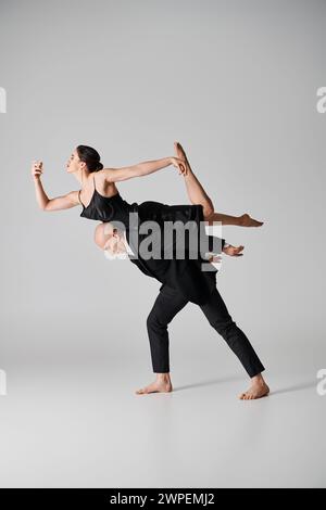 barefoot young woman in black dress balancing gracefully during dance performance with man Stock Photo