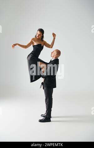 dancer lifting young brunette woman in black dress and high heels balancing during performance Stock Photo