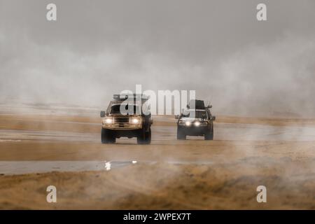 Two 4x4 cars driving along the foggy beach in search of adventure. Fraser Island, Queensland, Australia. Stock Photo